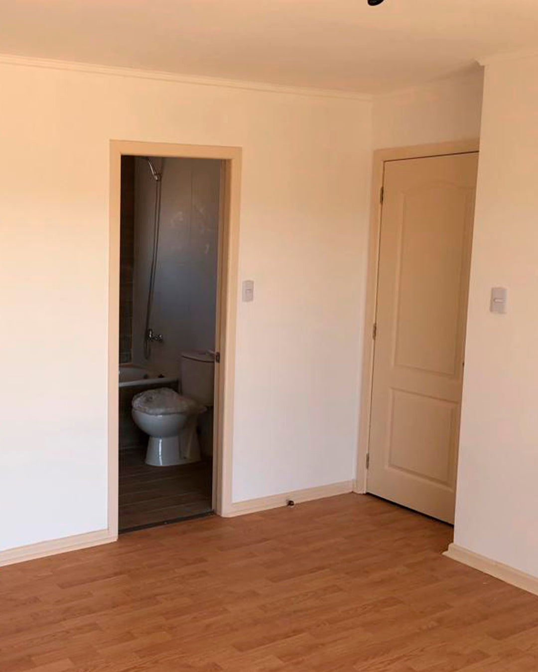 Dormitorio terminado con piso de madera y acceso a baño